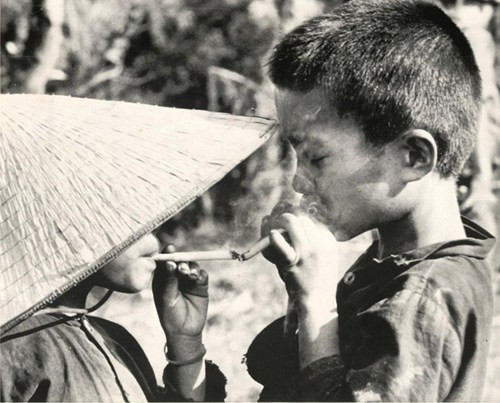 Hai cậu bé di tản từ vùng bờ biển Nam Đà Nẵng đang châm thuốc lá cho nhau, 29/2/1968.
