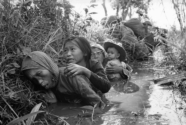 Phụ nữ và trẻ em cúi mình trong một con kênh bùn để tránh đạn trong một cuộc giao tranh tại một vị trí cách phía Tây Sài Gòn, ngày 1/1/1966 - một trong những bức ảnh kinh điển về chiến tranh Việt Nam của phóng viên ảnh Horst Faas.