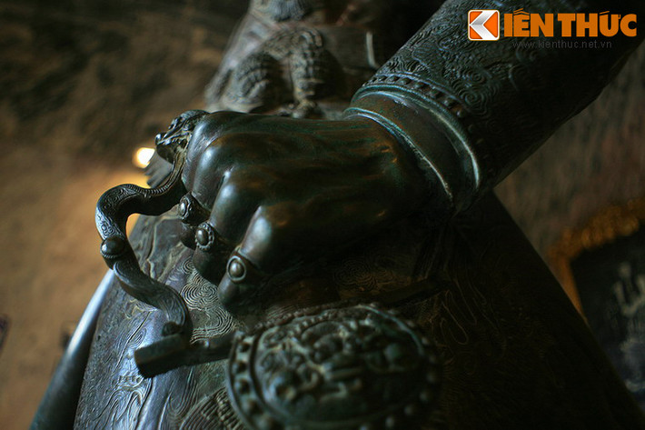 Tay trái của Vua Khải Định nắm chuôi gươm. Ba ngón tay đều đeo nhẫn mặt hoa nổi cao.