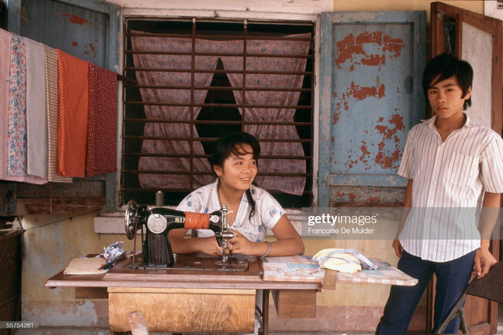 Cô thợ may làm việc bên hiên nhà.