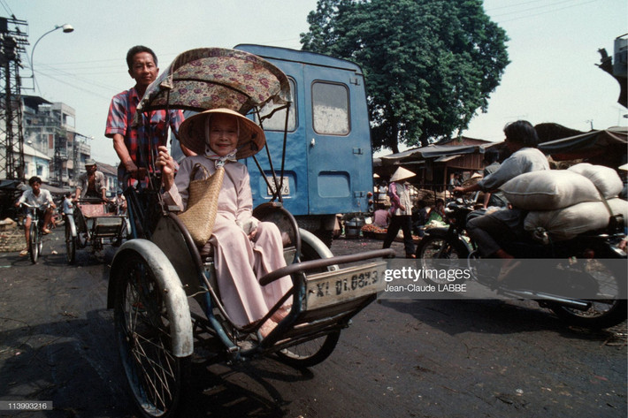 Cụ bà ngồi trên xích lô đi qua một khu chợ ở Sài Gòn vào ngày Giáng sinh năm 1994.