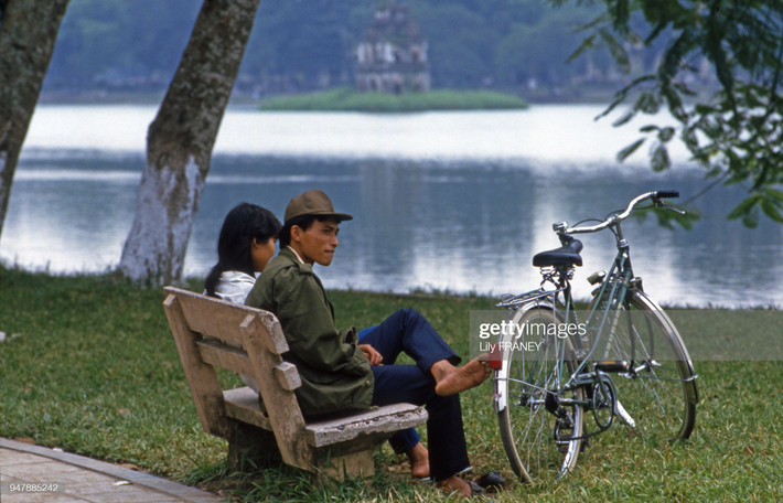 Một cặp đôi tình tứ trên ghế đá bờ hồ Hoàn Kiếm, Hà Nội năm 1987. Chiếc xe đạp Thống Nhất láng bóng là "vũ khí tán gái" rất hiệu quả của các chàng trai Hà Nội thời đó. Ảnh: Lily Franey / Getty Images.