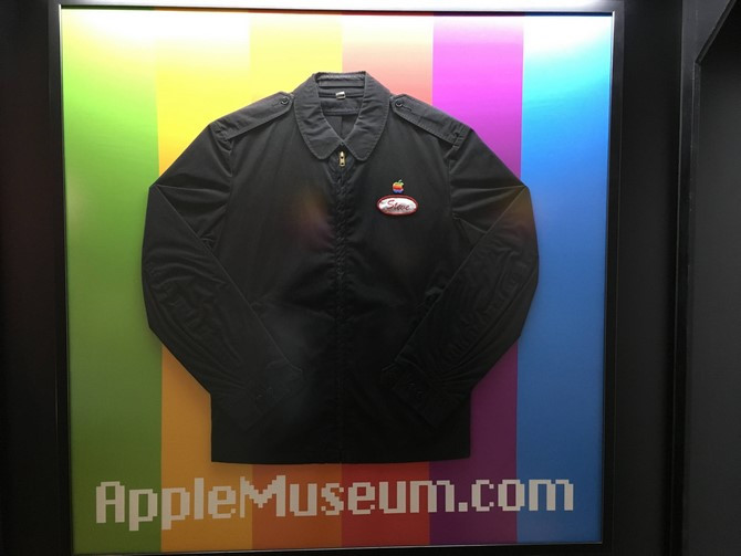Một chiếc áo khoác của Steve Jobs, trên áo có bảng tên của ông và logo Apple.