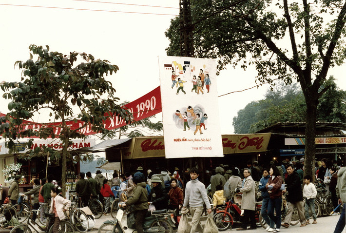 Khu chợ Tết ở Hà Nội dịp giáp Tết Canh Ngọ 1990. Tấm áp-phích treo giữa phố có nội dung "Nghiêm cấm ném pháo bừa bãi".