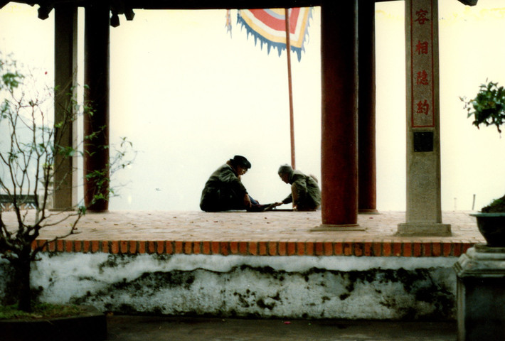 Đình Trấn Ba nhìn từ sân đền Ngọc Sơn. Hai cụ ông đang đánh cờ tướng ở đây.