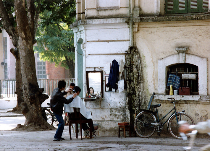 Cửa hàng cắt tóc vỉa hè tại một góc phố Hà Nội năm 1990. Ảnh: Diligam_te Flickr.