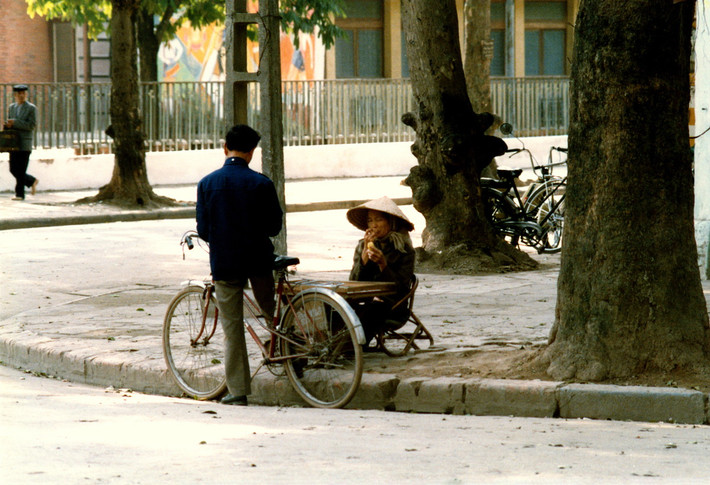 Một người đàn ông dừng chân bên quầy bán vé số vỉa hè.