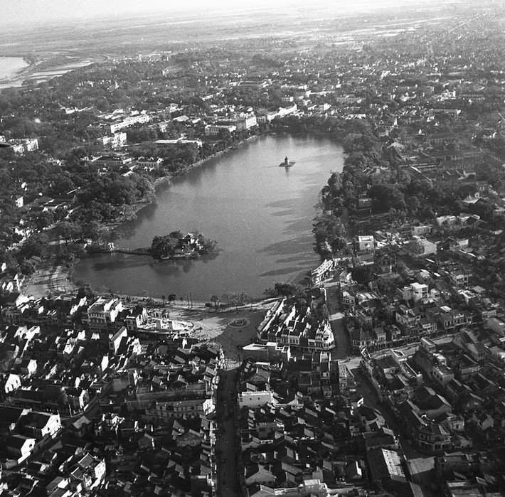 Hồ Gươm trong ráng chiều với bóng các hàng cây in xuống mặt hồ, thập niên 1950. Con đường ở phía dưới là Hàng Đào.