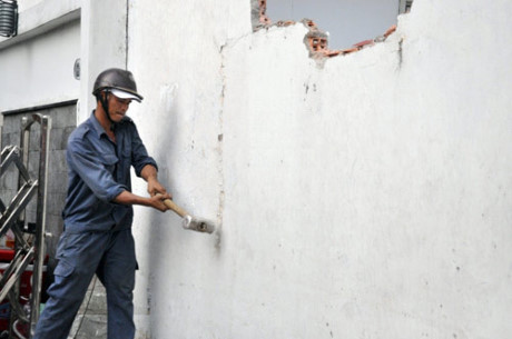 Công nhân dùng búa tạ để phá tường chiếm vỉa hè. Theo lực lượng trật tự đô thị quận, bức tường “khủng” của một doanh nghiệp nằm sát bên tòa nhà Bộ Công thương chiếm vỉa hè nên trước đó đơn vị đã gửi giấy cam kết tự tháo dỡ công trình vi phạm nhưng đến nay đã hết thời hạn cam kết mà vẫn chưa tháo dỡ nên bị phá bỏ.