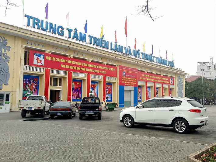 Ghi nhận của VietNamNet, sau lệnh cấm, hầu hết xế hộp không đỗ tại dải trung tâm nhưng lại chui vào công viên, leo lên vỉa hè. Khu vực công viên tượng đài nữ tướng Lê Chân nhiều ngày nay bỗng trở thành bãi ô tô mới. Ảnh: Mặt tiền trung tâm triển lãm bị xe biển xanh bủa vây