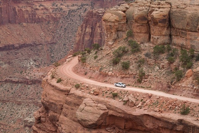 Một chiếc xe tải chạy dọc con đường đất bên vách đá ở Vườn Quốc gia Canyonlands, Utah, Mỹ.