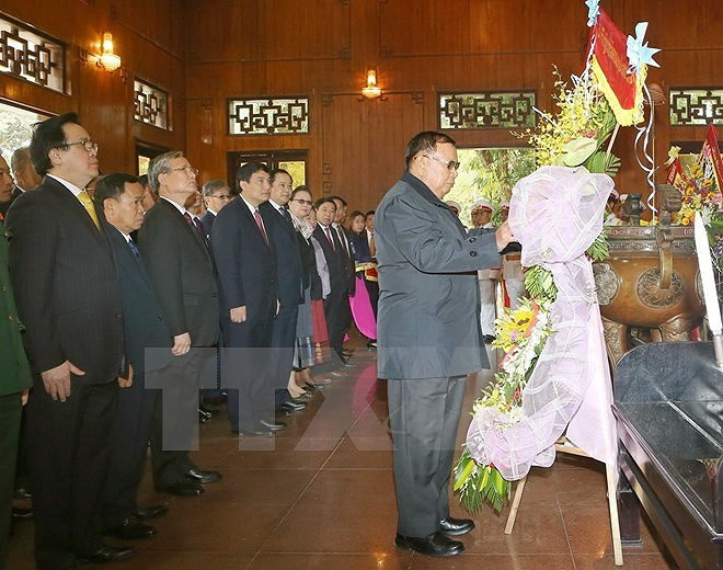 Trước đó, sáng 21/12, Tổng Bí thư, Chủ tịch nước Lào Bounnhang Vorachith và đoàn đại biểu cấp cao của Đảng, Nhà nước Lào đã đến dâng hương, dâng hoa tưởng niệm Chủ tịch Hồ Chí Minh tại Khu Di tích Kim Liên, xã Kim Liên, huyện Nam Đàn, tỉnh Nghệ An; thăm nhà lưu niệm của Chính phủ nước Cộng hòa Dân chủ Nhân dân Lào tặng Khu lưu niệm Chủ tịch Hồ Chí Minh tại Khu Di tích Kim Liên. (Ảnh: TTXVN)