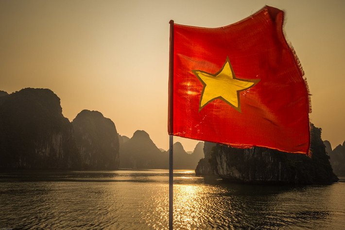 Lá quốc kỳ hiên ngang trước sóng gió, hình ảnh chụp từ một con thuyền trên vịnh Hạ Long. Ảnh: Chris / Flickr.com.