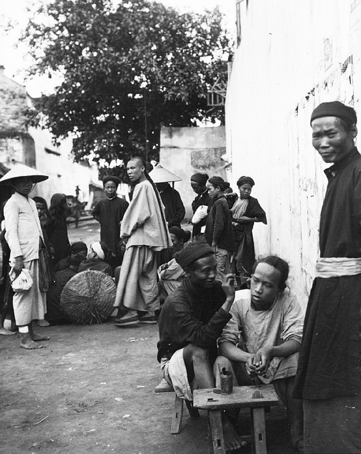 Một thanh niên đang được lấy ráy tai giữa phố đông người, Hà Nội năm 1896. Đây là việc bình thường với người địa phương, nhưng người Pháp hiếm khi dám thử, dù cảm thấy rất tò mò. Ảnh: Firmin-André Salles.