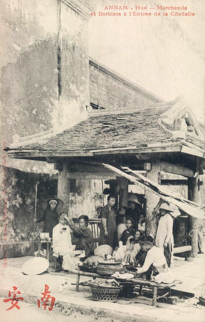Những người bán hàng và thợ hớt tóc dạo ở cổng thành Huế thập niên 1910.