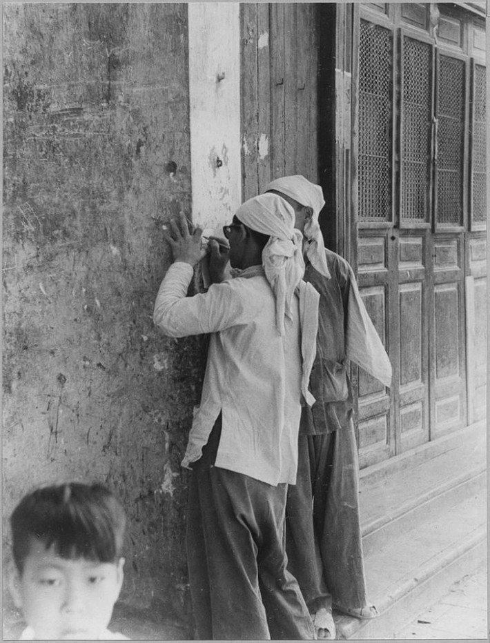 Hai tiểu thương chợ Đồng Xuân dùng mặt tường làm nơi giao dịch.