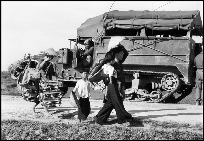 Người phụ nữ và những đứa con đi ngang qua chiếc xe quân sự của Pháp, 25/5/1954.