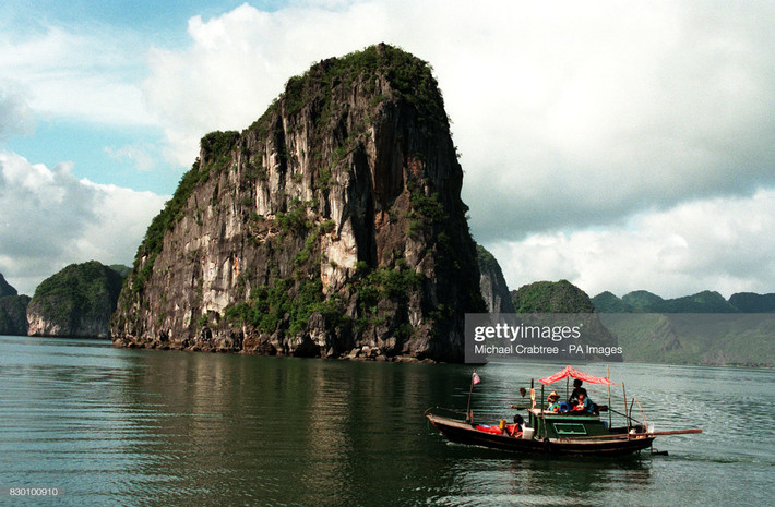 Con thuyền nhỏ bên khối đá khổng lồ của vịnh Hạ Long.