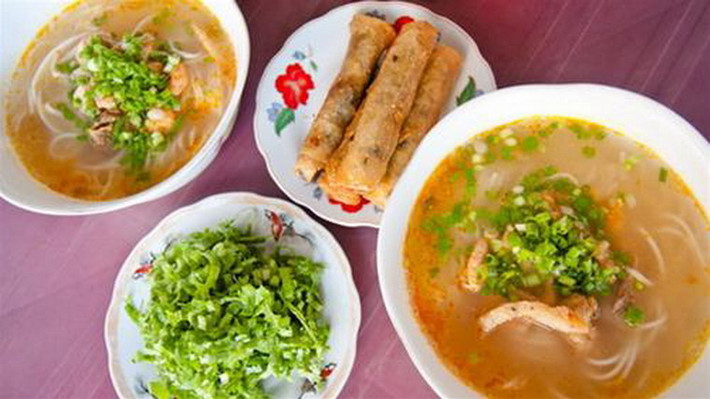 Giống như phở với người Hà Nội, cháo canh gắn bó với người Quảng Bình như thức ăn không thể thiếu vào buổi sáng. Món ăn này dùng các sợi mì to và dày, nước dùng nhiều và có màu vàng ươm của thịt cua, thịt đi kèm có sự kết hợp của cá, tôm, thịt nạc… Trong đó, cá lóc là nguyên liệu không thể thiếu. Những lát hành, ngò thái mỏng sẽ được rắc đều lên mỗi tô cháo canh đang bốc hơi nghi ngút để vội bưng đến cho khách thưởng thức kèm cải xanh thái nhỏ. Ảnh: Internet.