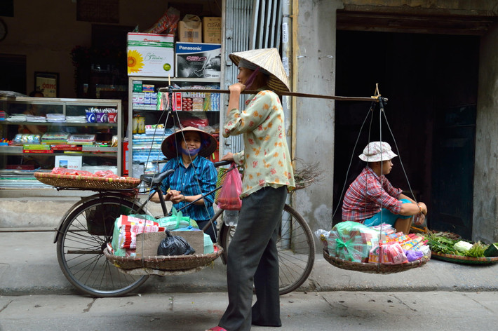 Những người bán hàng rong với quang gánh trên vai.