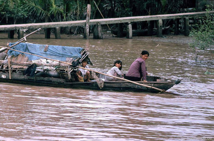 Người mẹ và hai đứa con trên con thuyền nhỏ bên một cù lao nổi giữa sông Tiền.