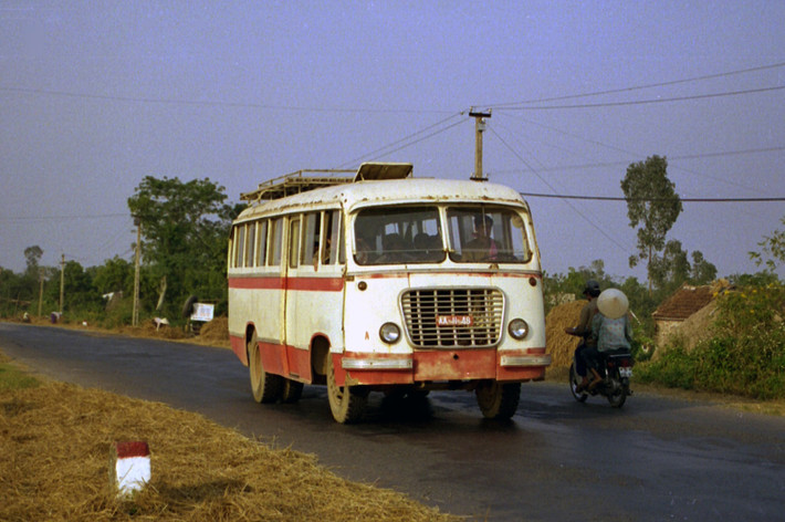Một chiếc xe buýt quân đội mang biển số AA-11-48 chạy trên con đường ngoại ô Hà Nội.