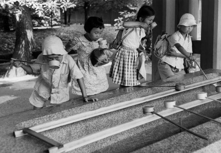 Các học sinh tiểu học uống nước ở lồi vào một ngôi đền Thần đạo ở Kyoto năm 1951. Ảnh: Werner Bischof.