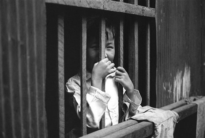 Nụ cười trẻ thơ phía sau song cửa của ngôi nhà ổ chuột ở Mả Lạng.