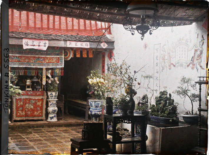 Nhìn sang bên phải, nơi có hòn non bộ trong bể nước, hoa thủy tiên và hoa đào đặt trên kệ bằng gỗ quý.