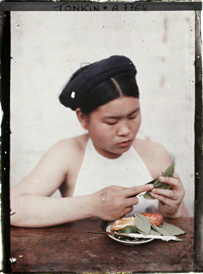 Thiếu nữ Hà Nội têm trầu, 1916. Để ăn trầu, người ta lấy lá trầu không cuộn nhiều vòng tròn, gài cuống lá vào cánh lá để giữ cho lá khỏi bung ra.