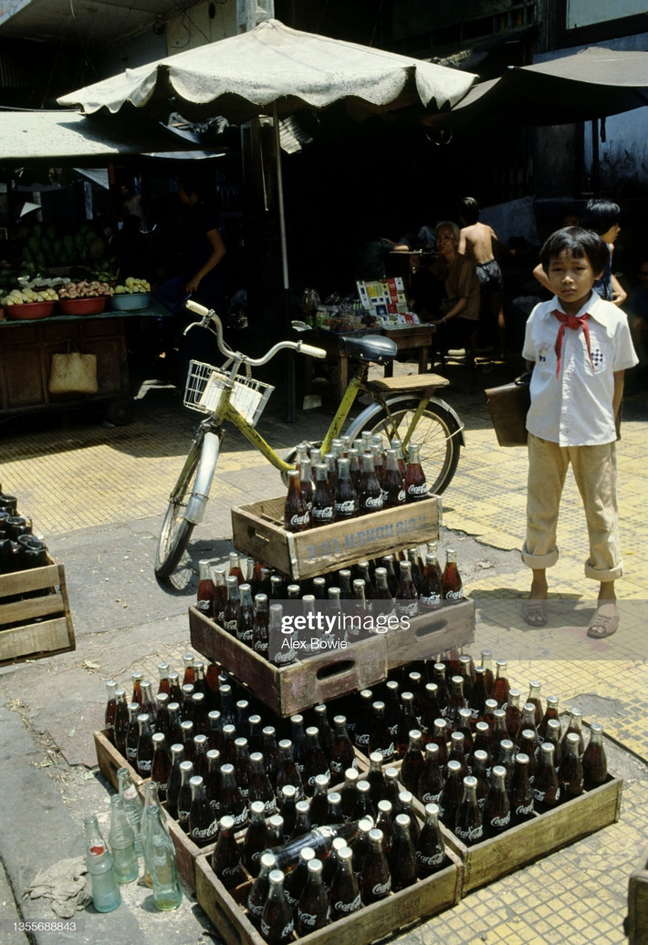 Cậu học sinh nhỏ tuổi đứng cạnh chồng Coca Cola.