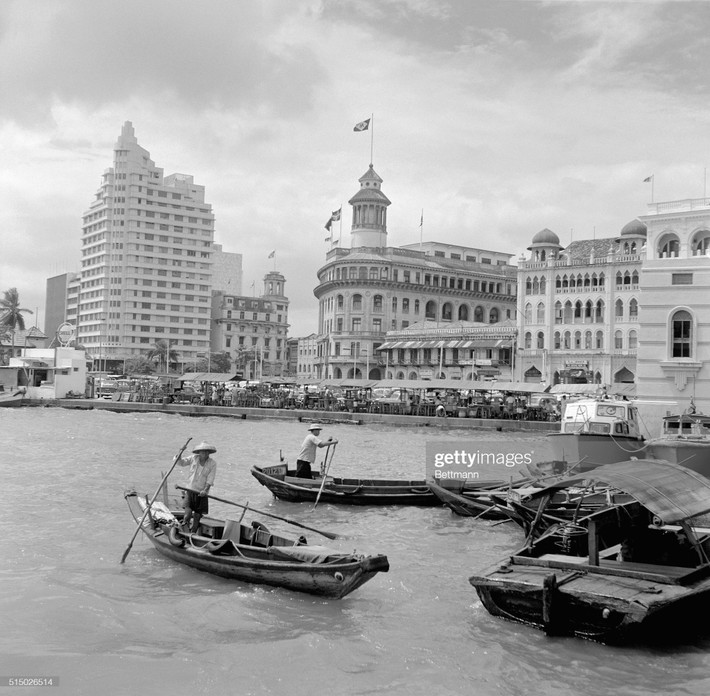Quang cảnh bờ sông Singapore với sự tương phản của Tòa nhà Bảo hiểm Châu Á mang phong cách kiến trúc hiện đại (trái), cao nhất trong thành phố, với các tòa nhà thời thuộc địa, tháng 10/1962. Trên mặt nước, thuyền tam bản chèo tay hoạt động đồng thời với thuyền máy tân tiến.