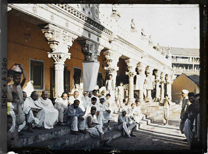 Những người đàn ông mặc đồ trắng ngồi trên bậc thềm của một ngôi đền Hindu.