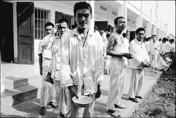 Bệnh nhân tâm thần xếp hàng nhận bữa ăn trưa ở "trại Trâu Quỳ". So với thời điểm những bức ảnh này được chụp, cơ sở vật chất của bệnh viện hiện tại đã có những bước tiến vượt bậc. Ảnh: Larry Towell/ Magnums.