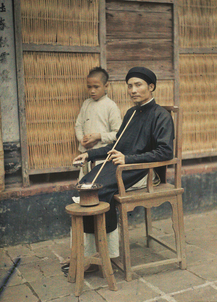 Ông lý trưởng hút thuốc lào trên sân nhà.