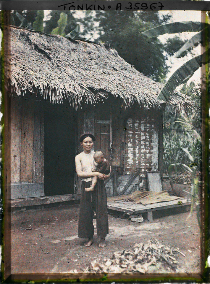 Bà mẹ bế con đứng trước hiên nhà, Bắc Bộ năm 1921. Ảnh: Léon Busy/Collections.albert-kahn.hauts-de-seine.fr.