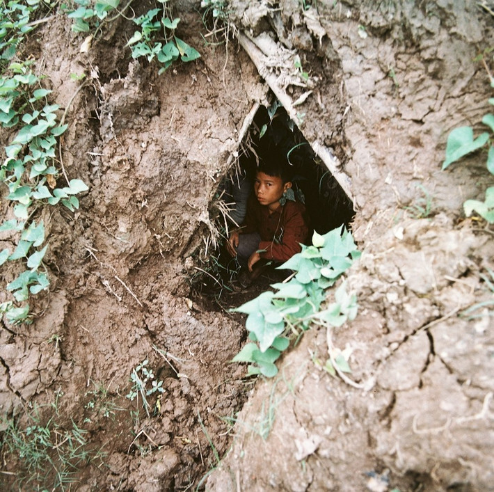 Chú bé ngồi trong hầm tránh bom.
