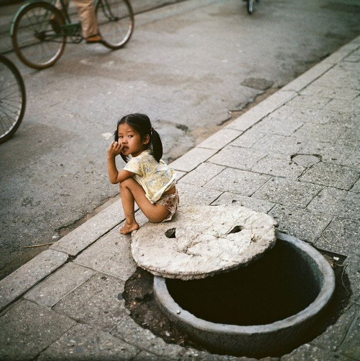 Bé gái ngồi bên miệng hầm trú ẩn.