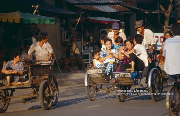 Em bé ngồi trên xe xích lô với mẹ.