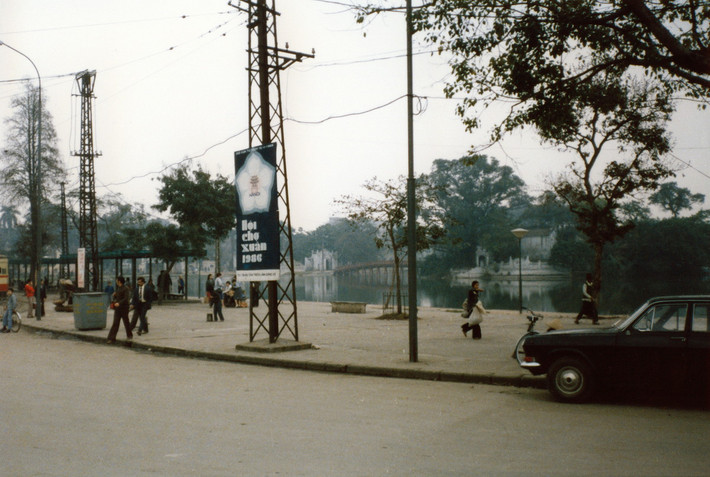 Bờ hồ Hoàn Kiếm, Hà Nội năm 1986. Bên phải là nhà chờ của bến tàu điện bờ hồ. Tấm áp-phích treo trên cột điện có nội dung "Hội chợ xuân 1986". Ảnh: Diligam_te Flickr.