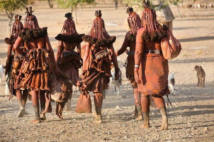 Bộ tộc Himba (Namibia) - Phủ đất đỏ lên người. Phụ nữ Himba sử dụng đất đỏ trộn với mỡ động vật để bôi lên da và tóc nhằm bảo vệ khỏi ánh nắng và côn trùng, đồng thời mang ý nghĩa làm đẹp và tôn vinh bản sắc dân tộc. Ảnh: Pinterest.