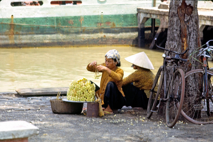 Hai phụ nữ bán mía ghim bên bờ sông Sài Gòn. Theo sự đổi thay của thời cuộc, các quầy mía ghim dần vắng bóng, và ngày nay đã "tuyệt tích" trên đường phố Sài Gòn. Ảnh: Thomas W. Johnson.