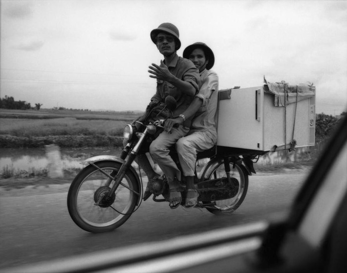 Xe máy Honda 67 chở tủ lạnh chạy trên Quốc lộ 5 giữa Hà Nội và Hải Phòng.