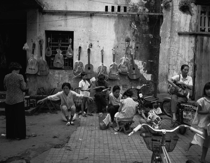 Xe Honda Cub dựng trước cửa hàng bán đàn guitar vỉa hè TP HCM.