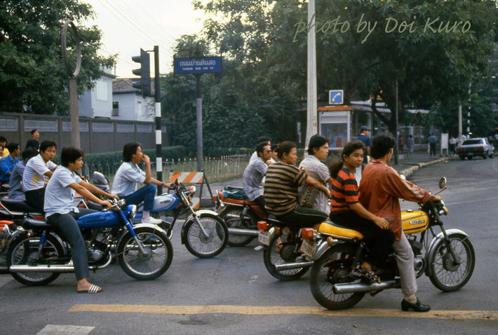 Những người trẻ di chuyển bằng xe máy trên đường phố Bangkok.