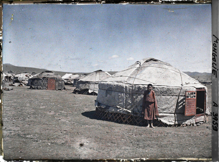 Một thiếu niên đứng dựa vào lều yurt.