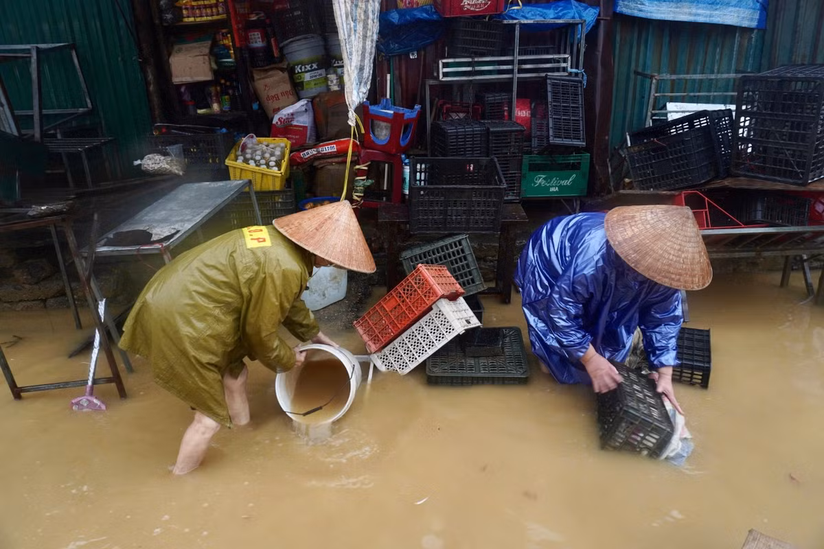 Cơn lũ lịch sử rút dần để lại ngổn ngang bùn đất. Trước đó, bà con trong chợ kê hàng hóa ở vị trí cao, song lũ lớn khiến đồ đạc trôi dạt khắp nơi gây khó khăn trong việc thu hồi. Hiện, mực nước tại đây đã xuống dưới đầu gối. Bà Nguyễn Thị Bảy (50 tuổi, người bán hoa quả tại chợ) cho biết dù rất ngán cảnh dọn lũ từ nhà đến kiosk ở chợ, bà chỉ mong nước rút để công việc trở lại. "Trời lại mưa nhưng thôi mưa giúp trôi bùn cũng được", bà nói. Ảnh: Quốc Anh.