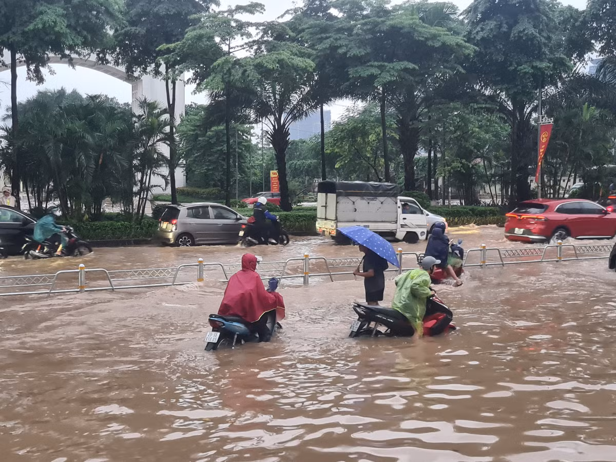 Nước ngập đến hơn nửa bánh xe máy khiến xe chết máy, người dân phải dắt bộ.