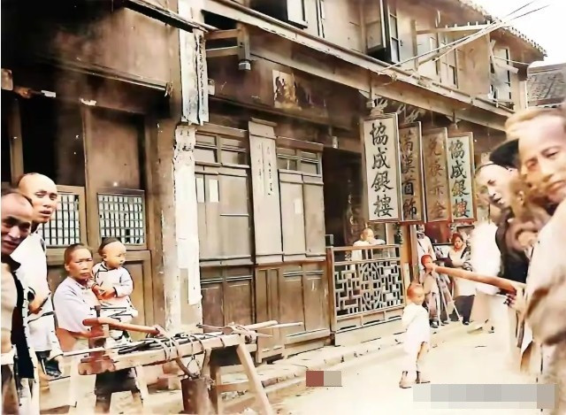 Một bức ảnh chụp cảnh đường phố, nơi người dân lần đầu tiên nhìn thấy máy ảnh với vẻ mặt đầy tò mò và thích thú. Thời đó, hầu hết người dân đều để kiểu tóc cạo nửa đầu và tết tóc đuôi sam dài phía sau.