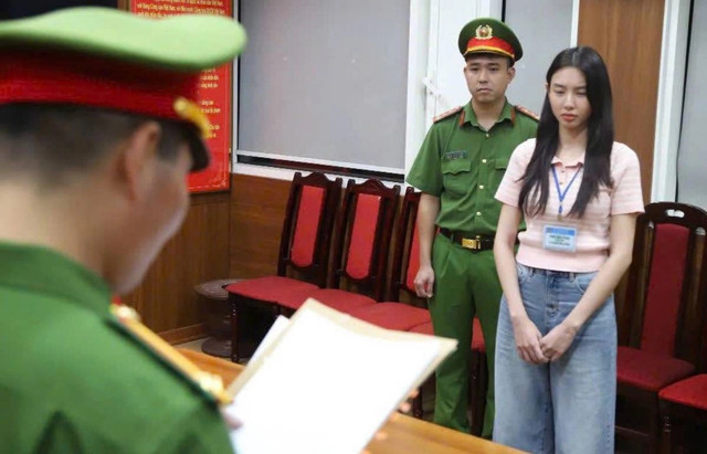 Hoa hậu Thùy Tiên (phải) nghe cảnh sát đọc lệnh khởi tố, bắt tạm giam. Ảnh: Bộ Công an. thuy-tien.png
